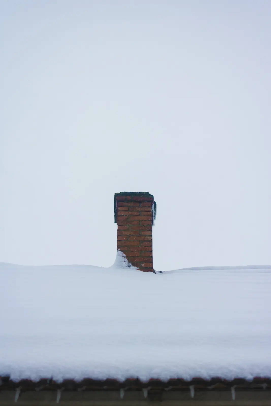Brick chimney on a snow-covered roof